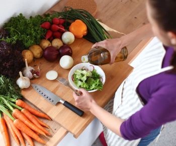 man dressing salad with oil